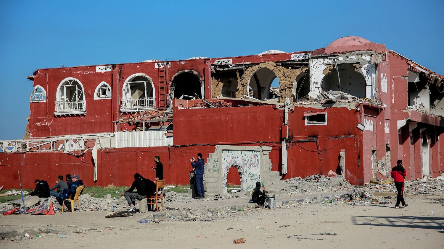 Des habitants palestiniens devant l'hôtel Al-Deira, endommagé par des bombardements israéliens, le 6 janvier 2024. (AFP)